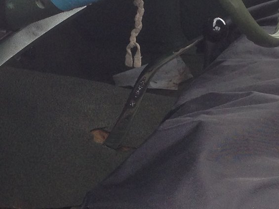 Car interior shot showing a floor shifter with a rope tied to it. Some paper is visible under the shifter