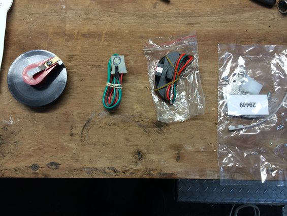 Distributor rotor, wiring harness, and ignition module parts laid out on a wooden workbench
