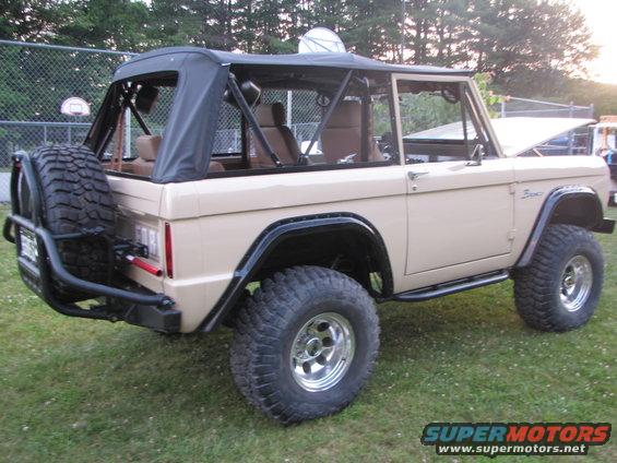Tan 1979 Ford Bronco with soft top, spare tire on rear bumper, and roll cage