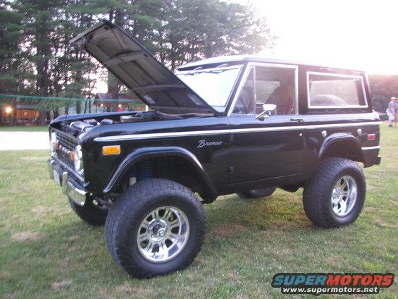 Black 1979 Ford Bronco with hood open, lifted suspension, and chrome wheels