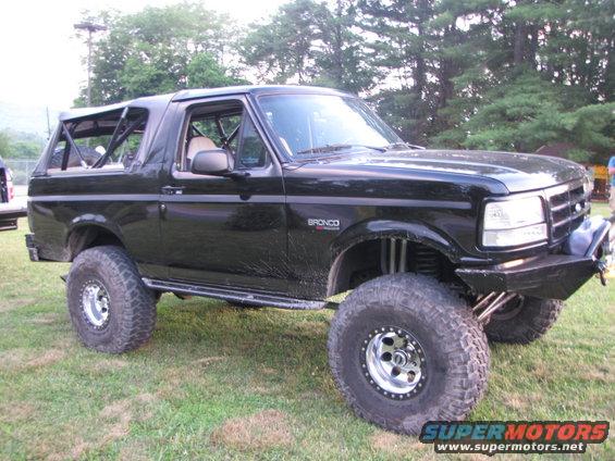 Black lifted Ford Bronco with roll cage, aftermarket bumper, and large off-road tires