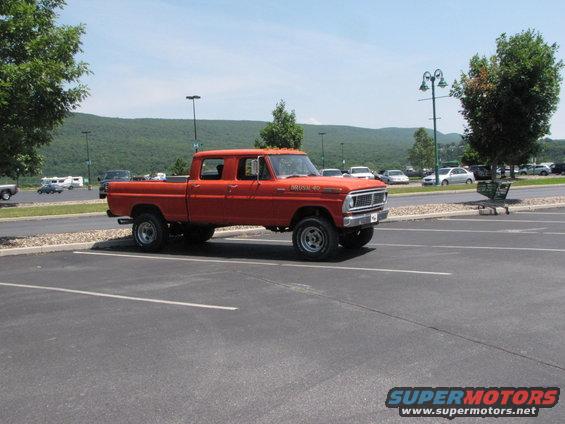 Orange crew cab pickup truck parked in a lot, with "BRONCO 40" text on the fender