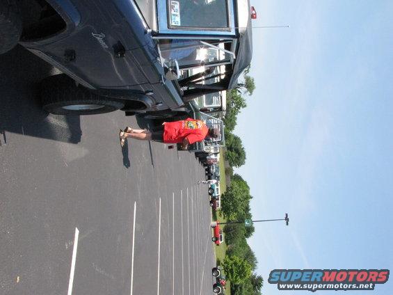 Dark blue 1979 Ford Bronco side view with a person standing beside it