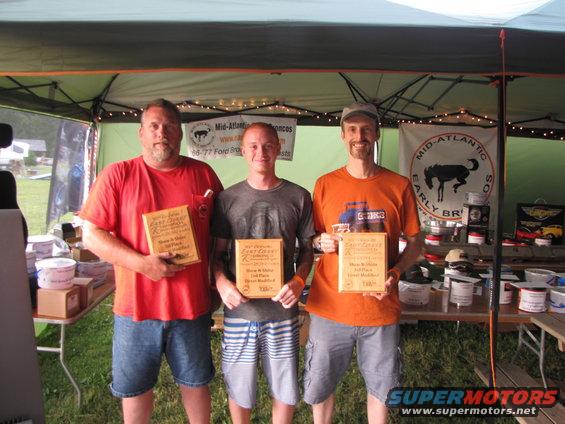 Three men with trophies at an event with Bronco logos