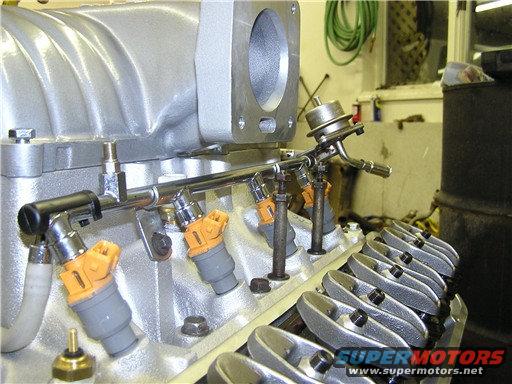 Close-up of Ford V8 engine fuel rail with orange-top injectors and valve covers