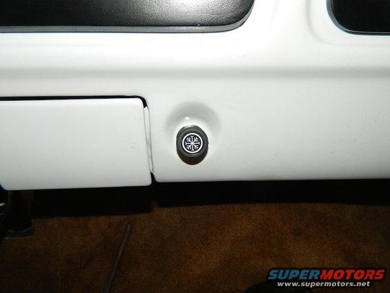 Close-up of a round black and white air conditioning control knob with a snowflake symbol on a white dashboard