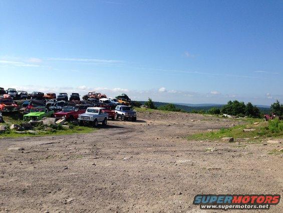Silver 1980s Ford Bronco parked in a junkyard with other vehicles