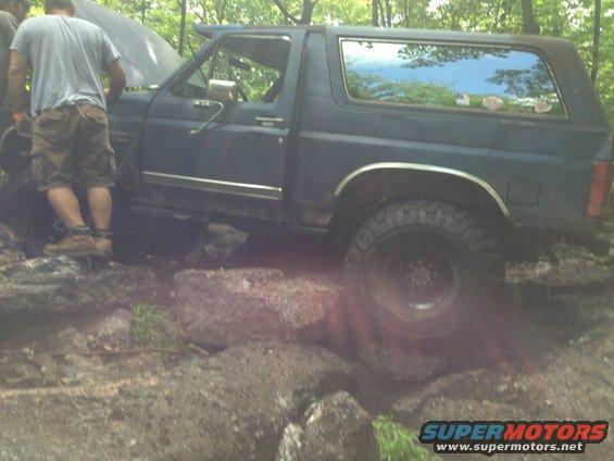 Dark blue Ford Bronco navigating rocky terrain with hood open
