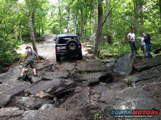 1988 Ford Bronco navigating a rocky trail with people watching