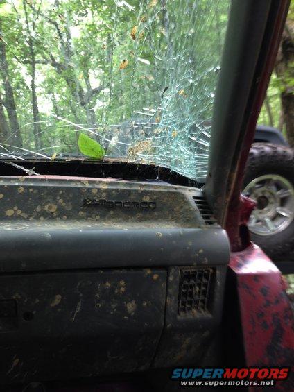 Interior of a red off-road vehicle with a cracked windshield and muddy dashboard