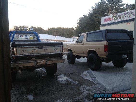 Rear view of a 1970s Ford pickup truck and a tan Ford Bronco parked outside