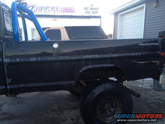 Side view of black 1970 Ford F-250 Sport Custom pickup with blue roll bar