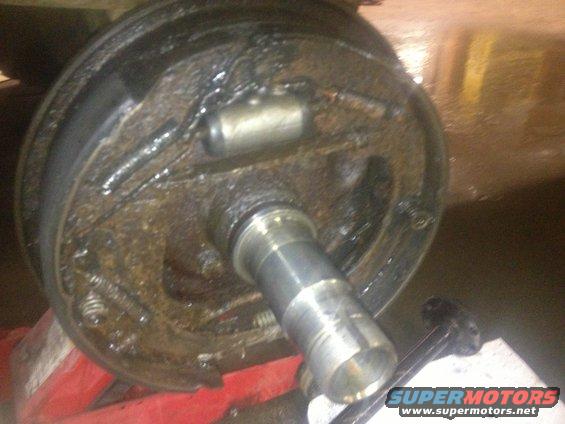 Close-up of a rusty brake drum assembly with brake shoes and a wheel cylinder visible