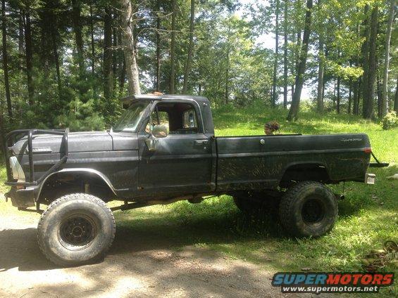 Side view of a black 1970 Ford F-250 pickup truck with a brush guard and lifted suspension