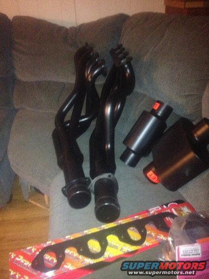 Black exhaust headers and mufflers on a couch with gaskets in the foreground