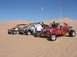 1993 Ford Taurus - Several dune buggies are parked on a sandy desert landscape under a clear blue sky.