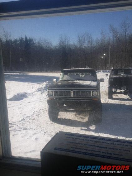 Front view of a black 1970 Ford F-250 in snow