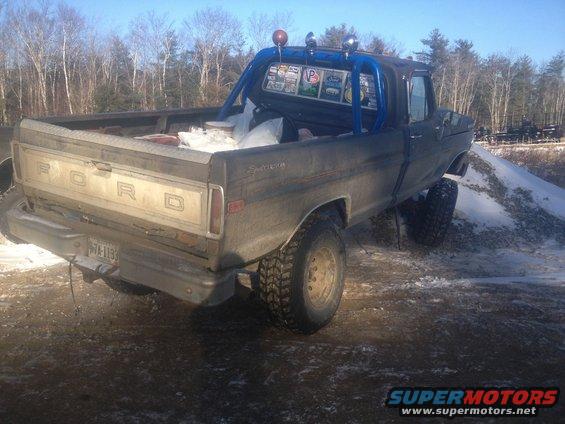 Dark gray 1973 Ford F-250 pickup truck with a blue roll bar, seen from the rear