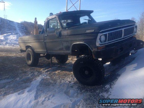 1970 Ford F-250 pickup truck with large tires and lift kit parked on snowy ground