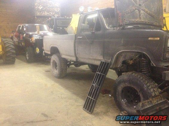 Gray pickup truck with hood open, black pickup truck behind it