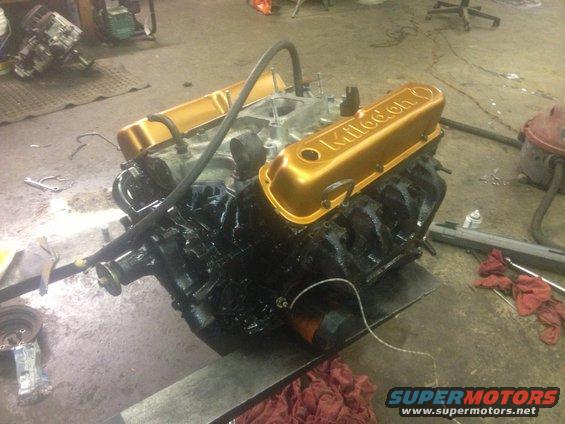 Engine with gold "Kultool" valve covers on a stand in a workshop