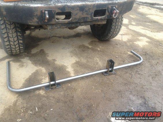 rear of a truck with a custom bumper and a tow hitch assembly lying on the ground in front of it