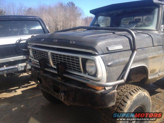 1970 Ford F-250 front end with chrome grille, custom brush guard, and aftermarket bumper. Another truck is partially visible to the left
