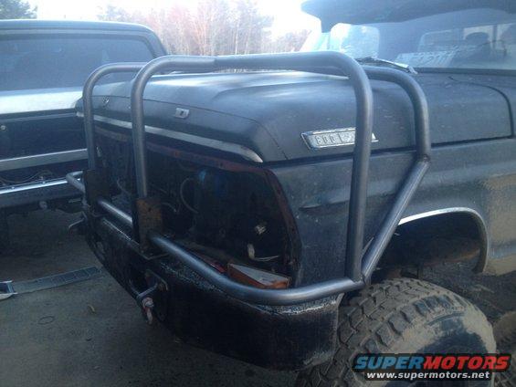 Ford truck front end with a large metal bumper and grille guard. Another vehicle is visible to the left