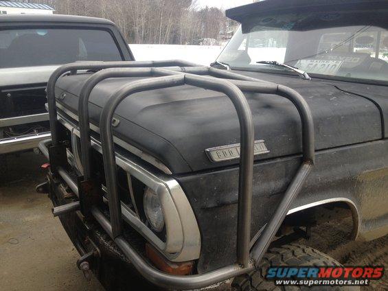 Front view of a black Ford truck with a large metal brush guard. Another truck is visible behind it