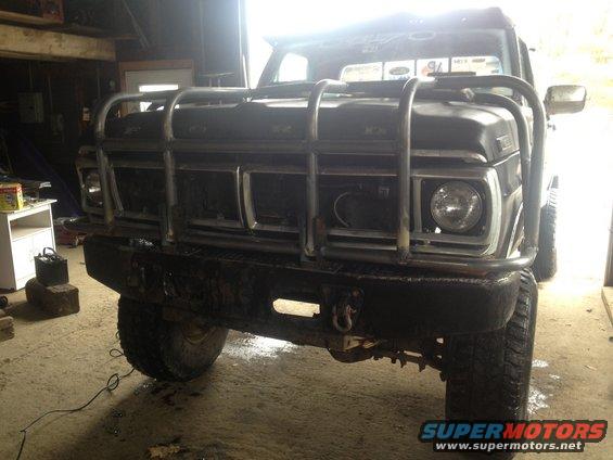 Black Ford truck with a large metal grille guard and aftermarket bumper. The truck is in a garage