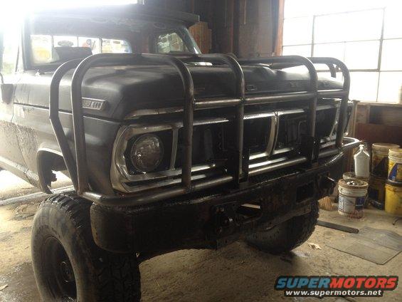Front view of a black 1970 Ford F-250 with a custom bull bar and large tires
