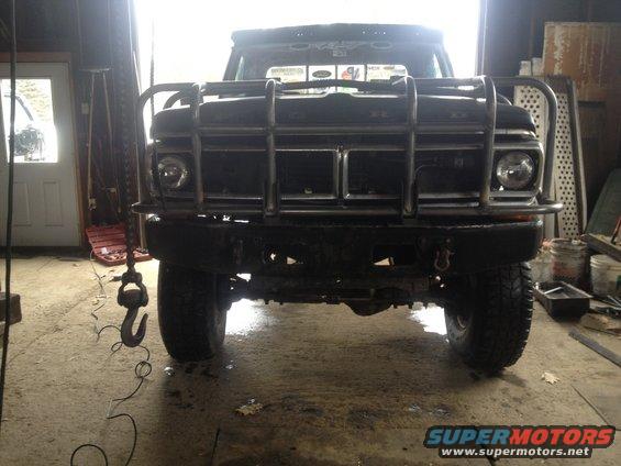 Black 1970 Ford F-250 with a large front brush guard, seen head-on in a garage