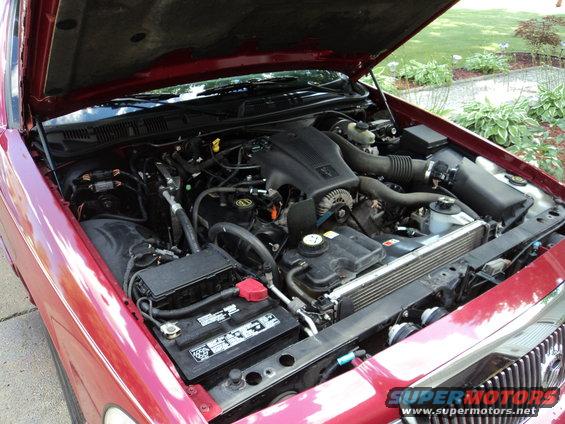 2004 Mercury Grand Marquis engine bay with hood open, showing V8 engine, battery, and radiator
