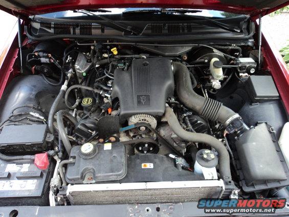 Engine bay of a 2004 Mercury Grand Marquis, showing the V8 engine, radiator, and battery