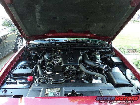 Red 2004 Mercury Grand Marquis engine bay with hood open, showing V8 engine components and battery