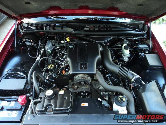 Red 2004 Mercury Grand Marquis engine bay with V8 engine cover and air intake visible