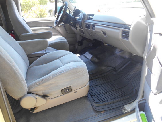 Interior of a 1994 Ford Bronco showing front seats, dashboard, and floor mats