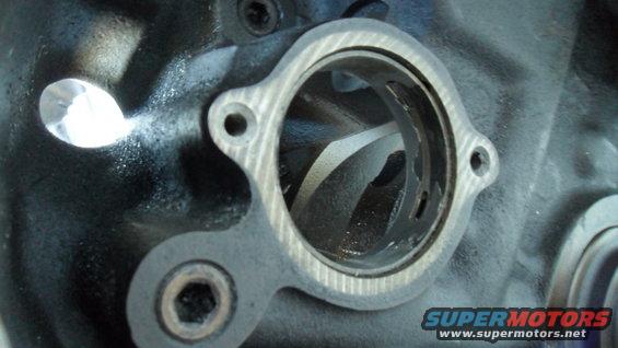 Engine cylinder head port with gasket and bolt holes, close-up