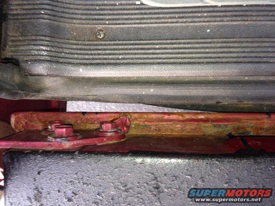 rusted metal bracket with bolts, part of a vehicle's undercarriage