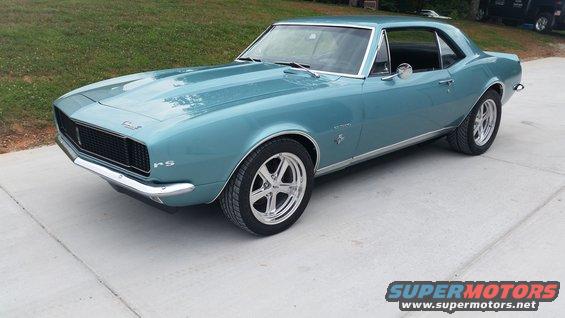 Teal coupe parked on concrete, front quarter view. Has 'RS' badge on fender