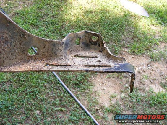 Close-up of a rusted metal bracket with several holes and slots