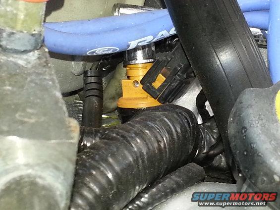 Close-up of a yellow fuel injector with blue hose and black wiring