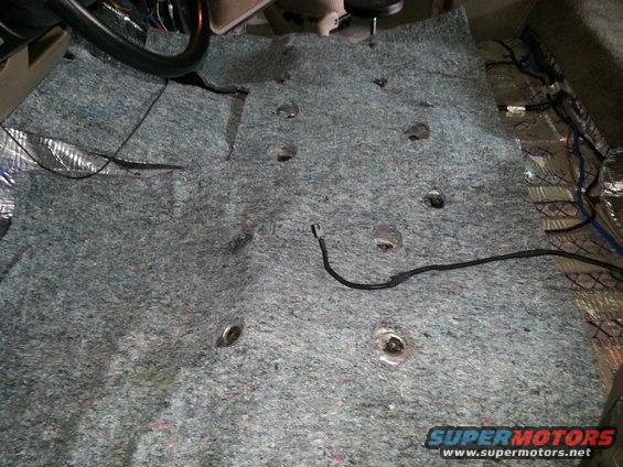 Carpet removed from vehicle floor, showing sound deadening material and wiring