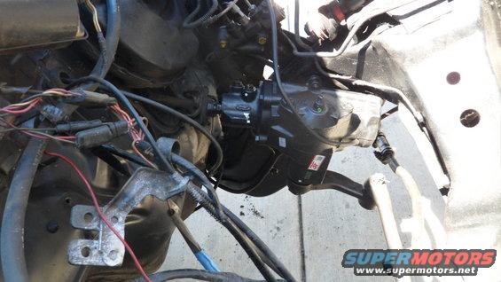 Close-up of a vehicle's steering gear box and linkage, with wiring harness visible