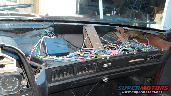 Car dashboard with exposed wiring and a blue electronic module