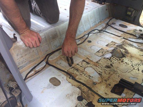 Interior floor of vehicle with wiring exposed, being cleaned