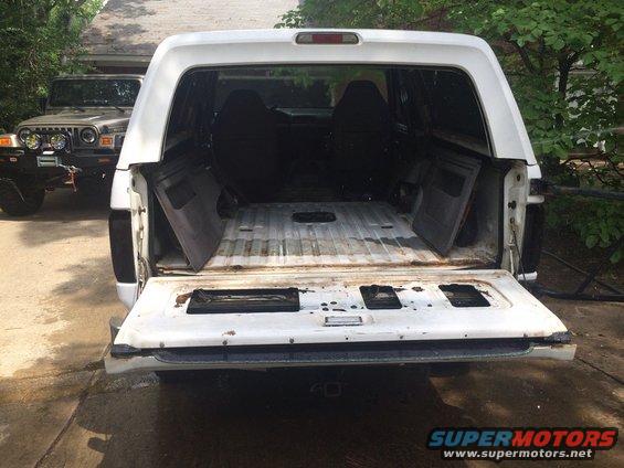 white SUV's open tailgate showing empty cargo area. Jeep in background