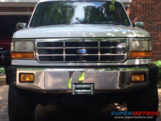 White Ford truck front view with chrome bumper and grille. Winch installed