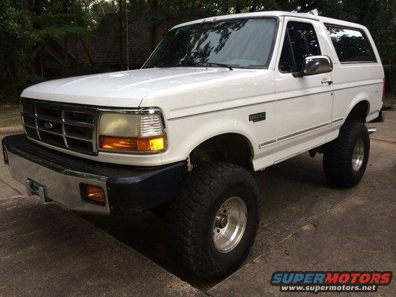 White 1994 Ford Bronco lifted with large tires, front 3/4 view