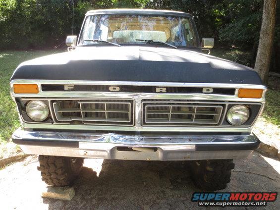 Ford truck grille with chrome bumper and orange turn signals. The word FORD is spelled out above the grille